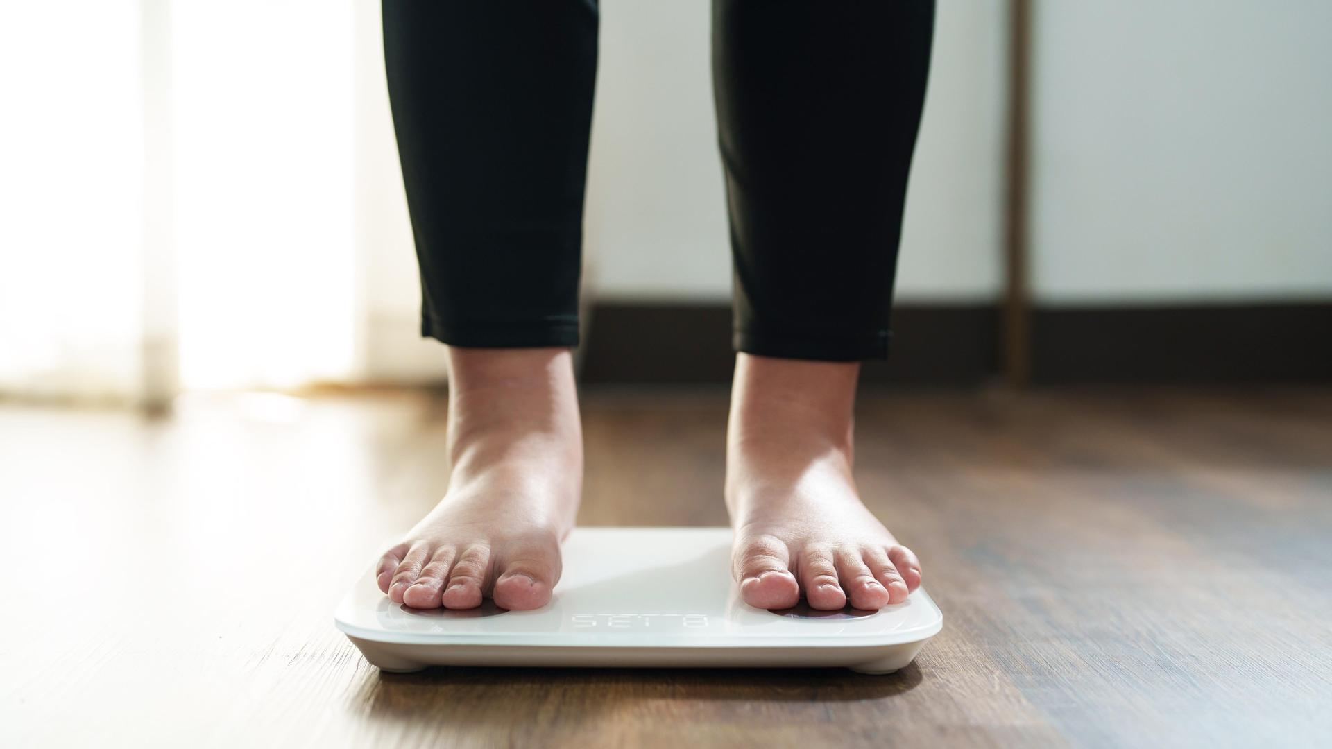Die Füße einer Frau stehen auf einer digitalen Waage für Kontrolle des Körpergewichts. Die Füße einer Frau stehen auf einer digitalen Waage für Kontrolle des Körpergewichts.