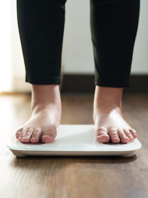 Die Füße einer Frau stehen auf einer digitalen Waage für Kontrolle des Körpergewichts. Die Füße einer Frau stehen auf einer digitalen Waage für Kontrolle des Körpergewichts.