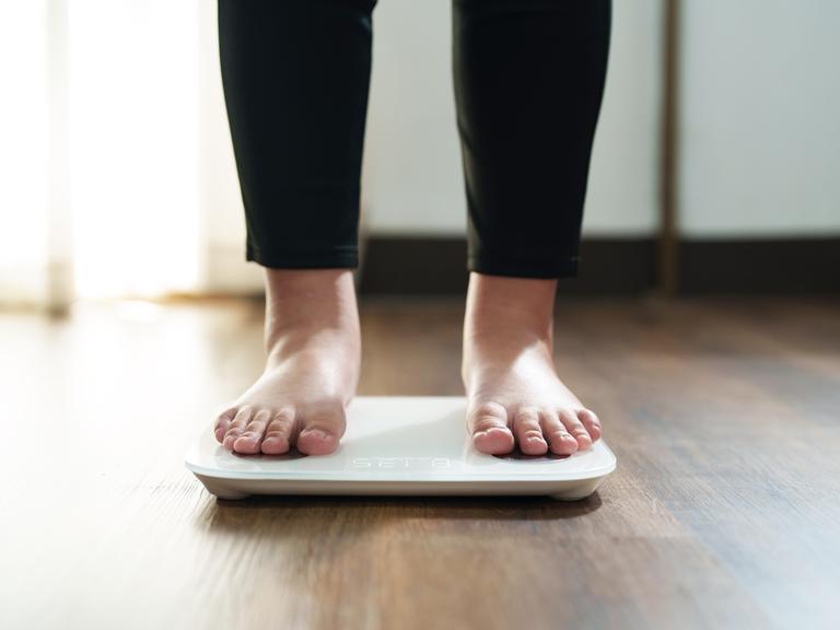 Die Füße einer Frau stehen auf einer digitalen Waage für Kontrolle des Körpergewichts. Die Füße einer Frau stehen auf einer digitalen Waage für Kontrolle des Körpergewichts.