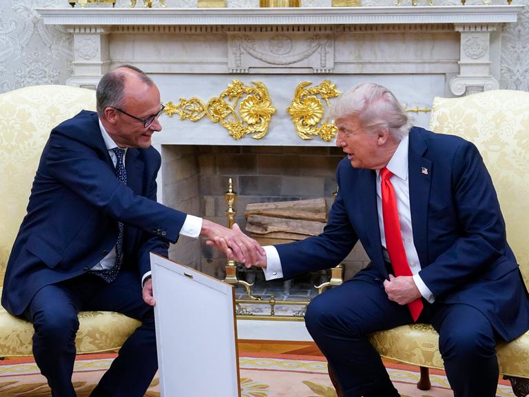 Bundeskanzler Friedrich Merz schüttelt im Oval Office die Hand von US-Präsident Donald Trump. In der anderen Hand hält Merz sein Gastgeschenk: ein gerahmtes Abbild der Geburtsurkunde von Trumps Großvater.