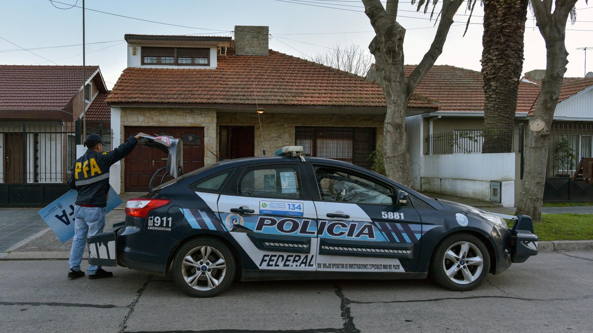 Ein Polizeiauto, an dem ein Mann hantiert, vor einem Haus im Viertel Mar del Plata in Argentinien Ein Polizeiauto, an dem ein Mann hantiert, vor einem Haus im Viertel Mar del Plata in Argentinien