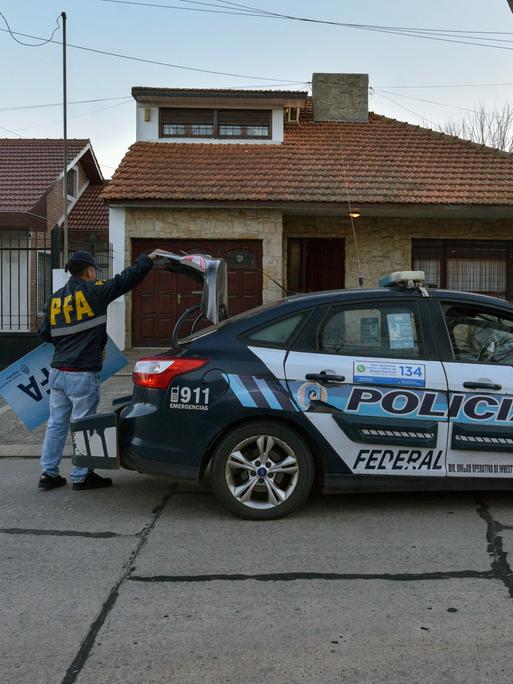Ein Polizeiauto, an dem ein Mann hantiert, vor einem Haus im Viertel Mar del Plata in Argentinien