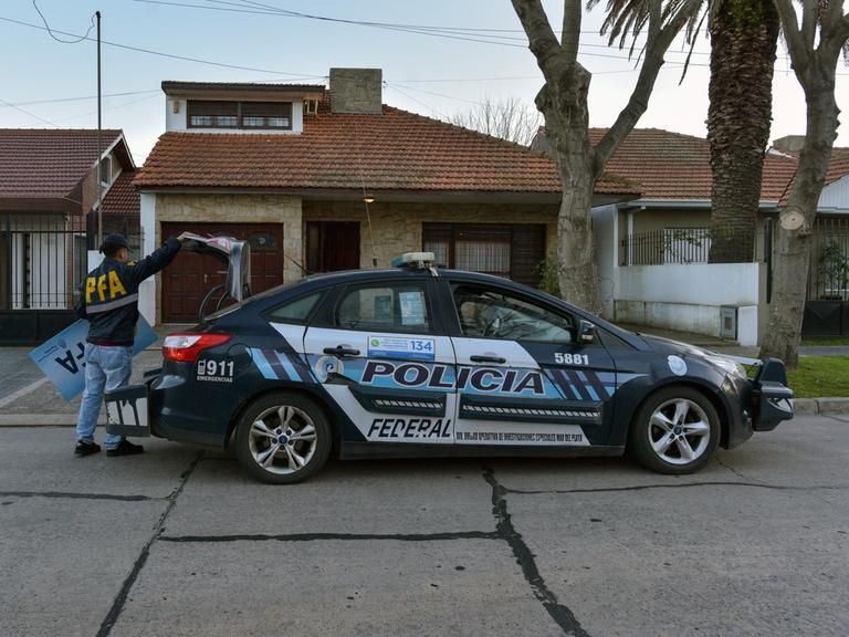 Ein Polizeiauto, an dem ein Mann hantiert, vor einem Haus im Viertel Mar del Plata in Argentinien