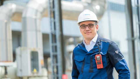 Eduard Schmitke, steht vor den Rohren des Gasspeichers und schaut für ein Porträt in die Kamera.