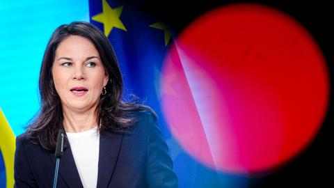 Annalena Baerbock vor einer Europafahne an einem Rednerpult.