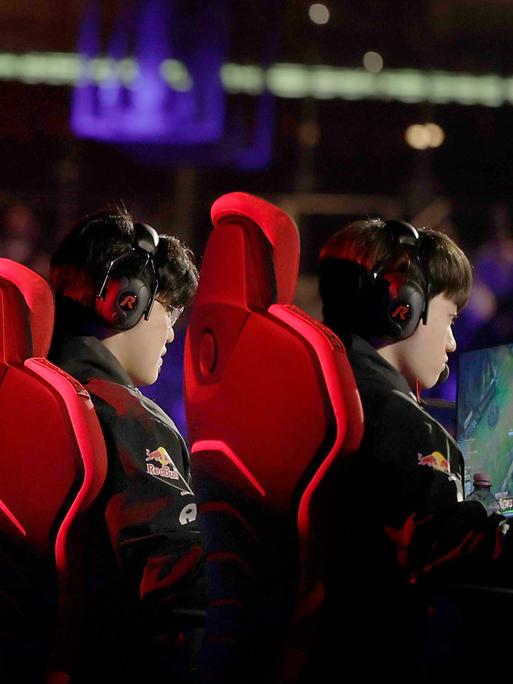 Spieler der koreanischen Mannschaft T1 spielen bei einem E-Sport-Showevent. Sie sitzen in roten Sitzen vor Bildschirmen.