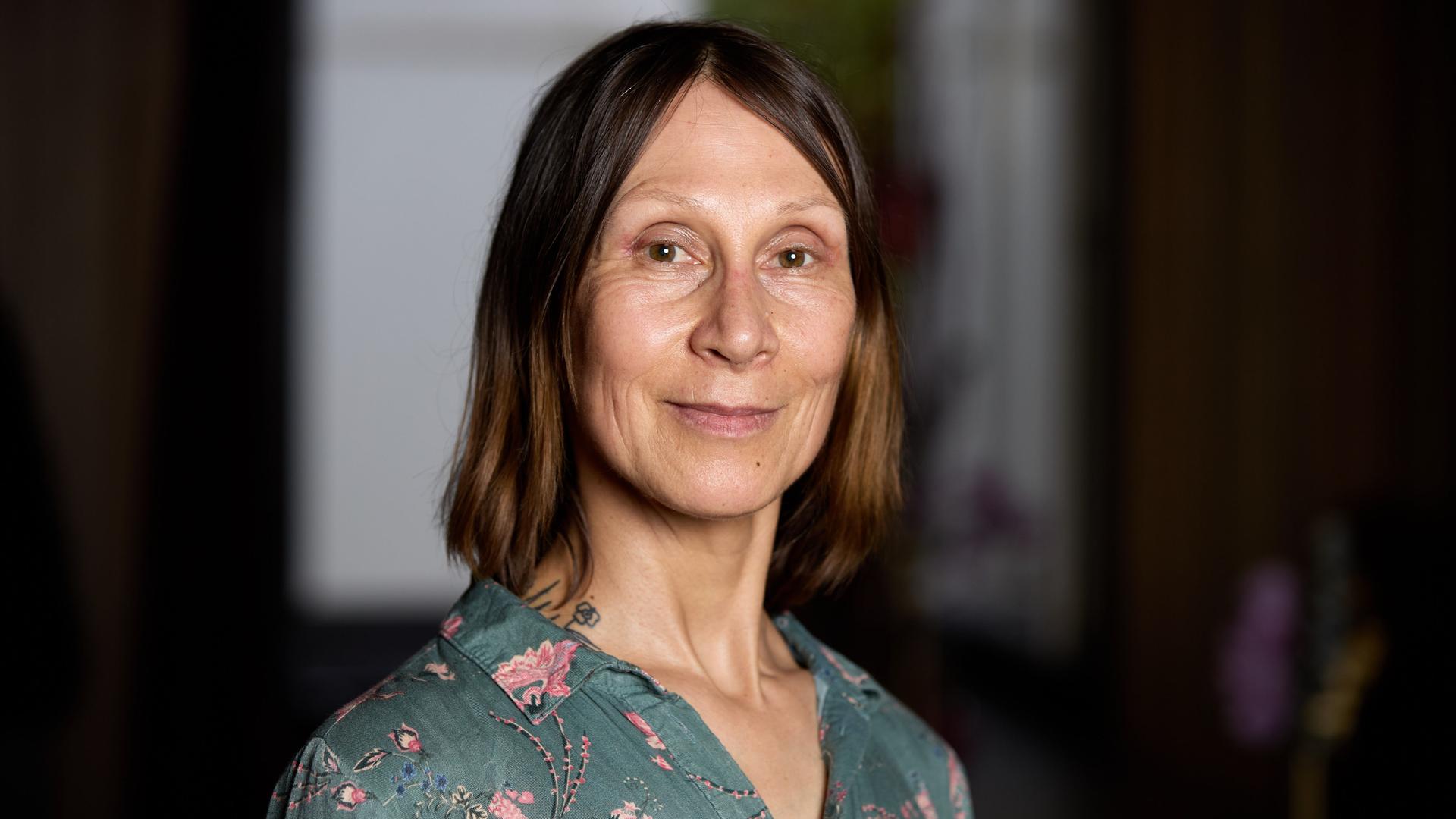 Eine Frau mit dünnen langen mittelblonden Haaren blickt lächelnd in die Kamera.