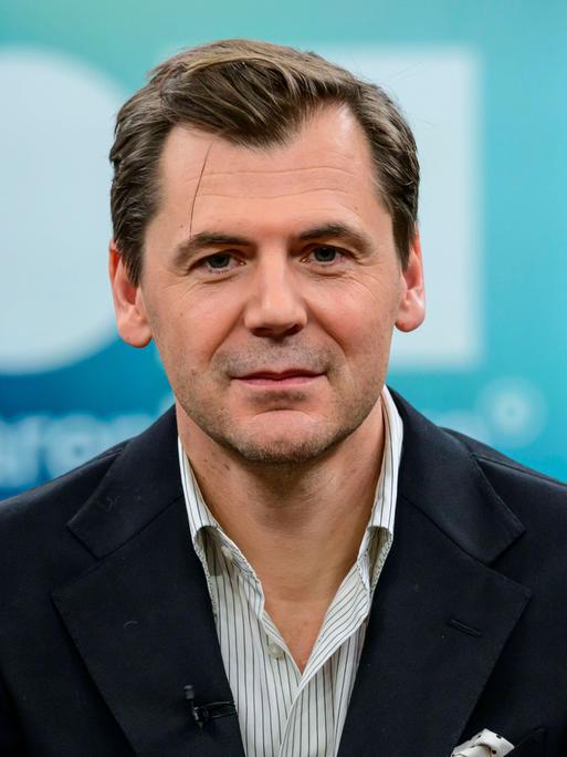 Der Autor, Publizist und Islamwissenschaftler Daniel Gerlach. Er schaut in die Kamera. Er trägt ein weiß gestreiftes Hemd und eine dunkle Jacke. 