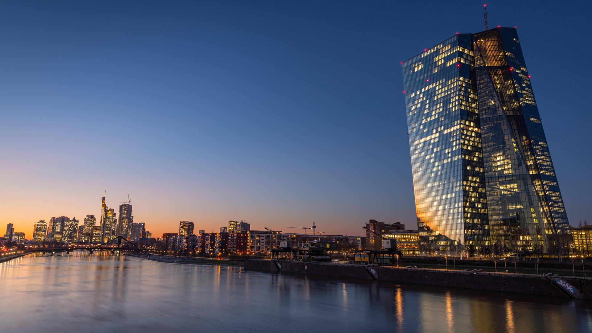 Die Lichter der Europäischen Zentralbank EZB und der Frankfurter Bankenskyline leuchten am Abend.