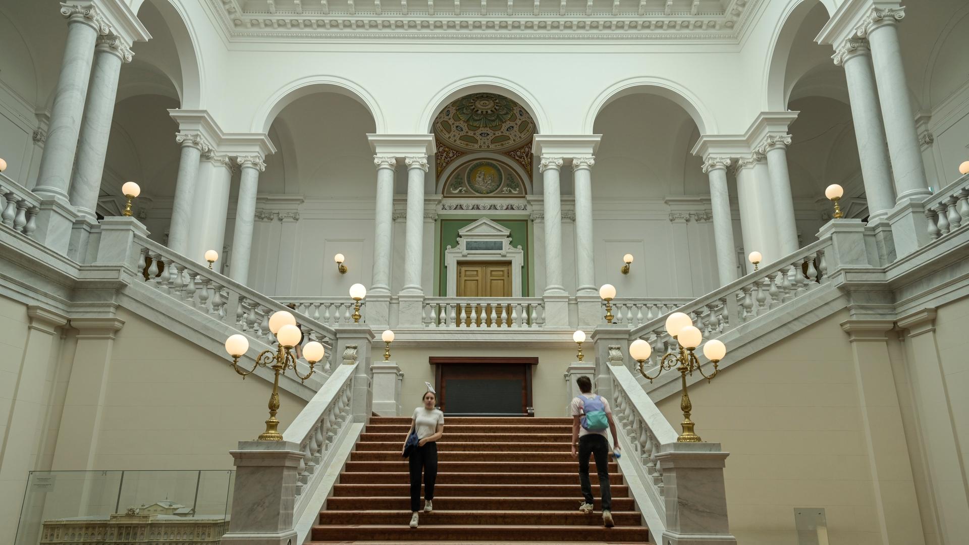 Zwei Studierende gehen im Treppenhaus der Universitätsbibliothek Leipzig.