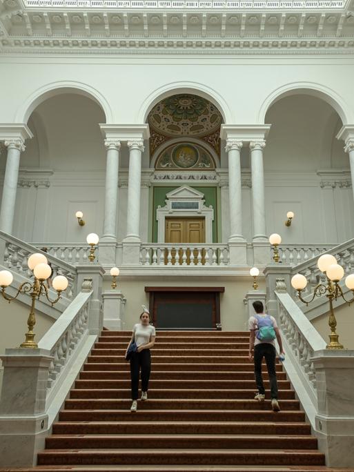 Zwei Studierende gehen im Treppenhaus der Universitätsbibliothek Leipzig.