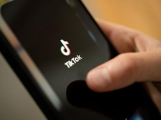 Ein Teenager tippt auf das TikTok-Logo auf einem Smartphone.