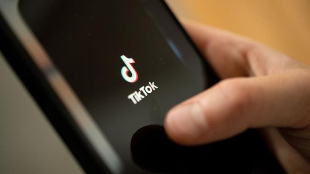Ein Teenager tippt auf das TikTok-Logo auf einem Smartphone.