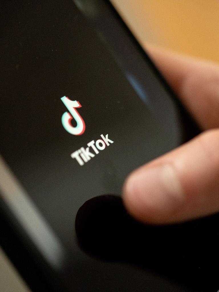 Ein Teenager tippt auf das TikTok-Logo auf einem Smartphone.