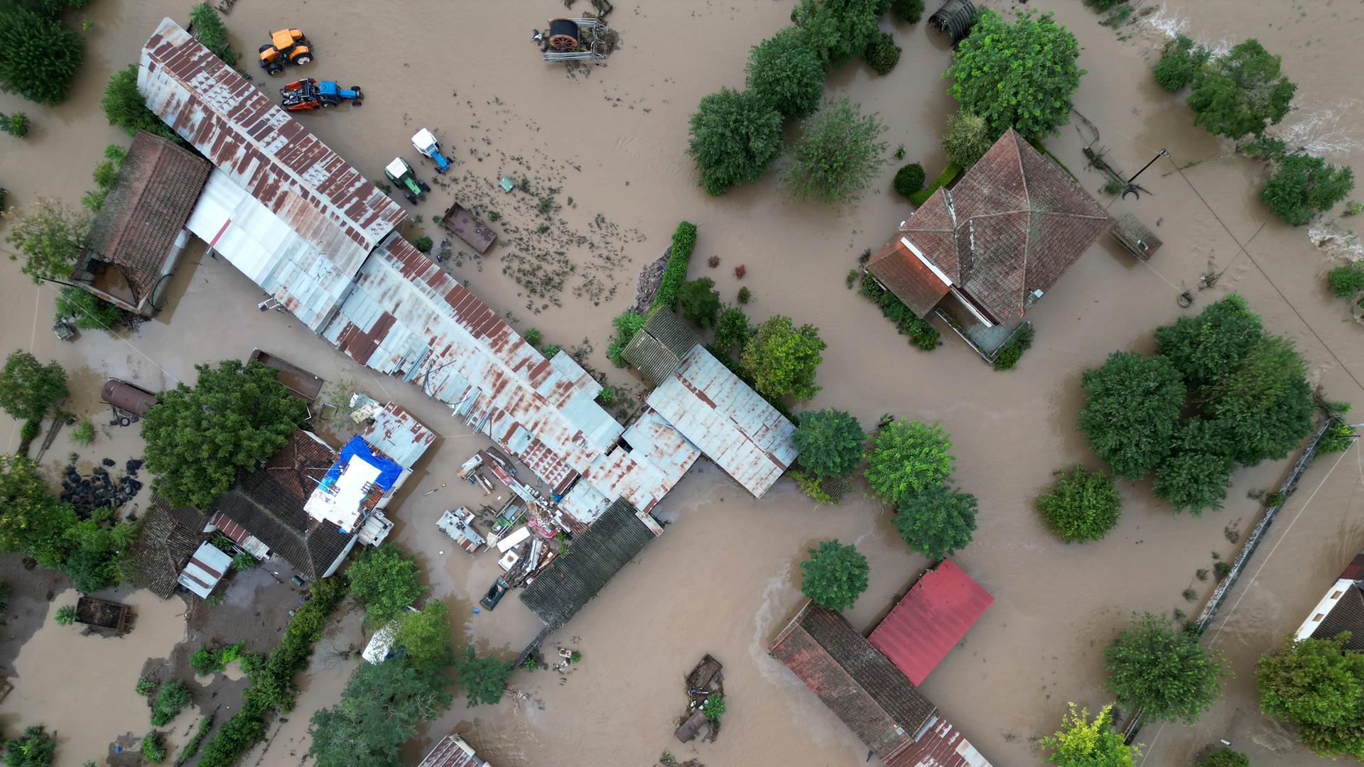 Senkrechter Blick aus der Luft nach unten auf die von braunem Wasser umgebenen Gebäude.