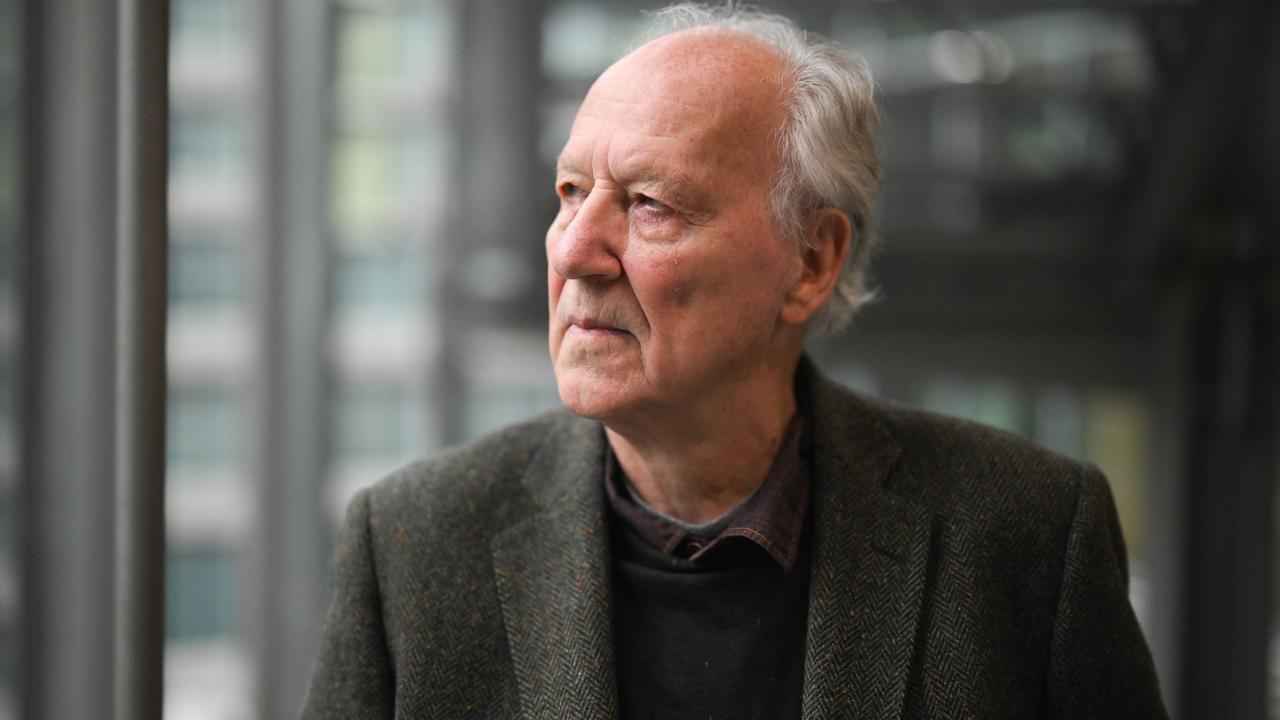 Werner Herzog; er schaut ernst nach rechts, trägt einen dunklen Blazer und einen dunklen Pullover. 