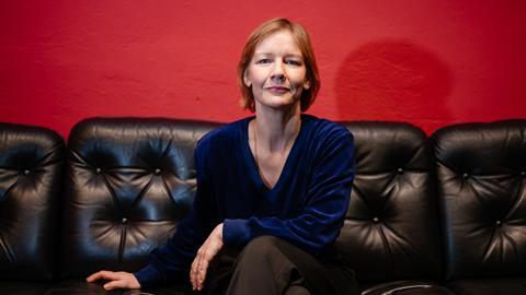 Die Schauspielerin Sandra Hüller sitzt auf einer schwarzen Couch in einem kleinen Saarbrücker Programmkino. 