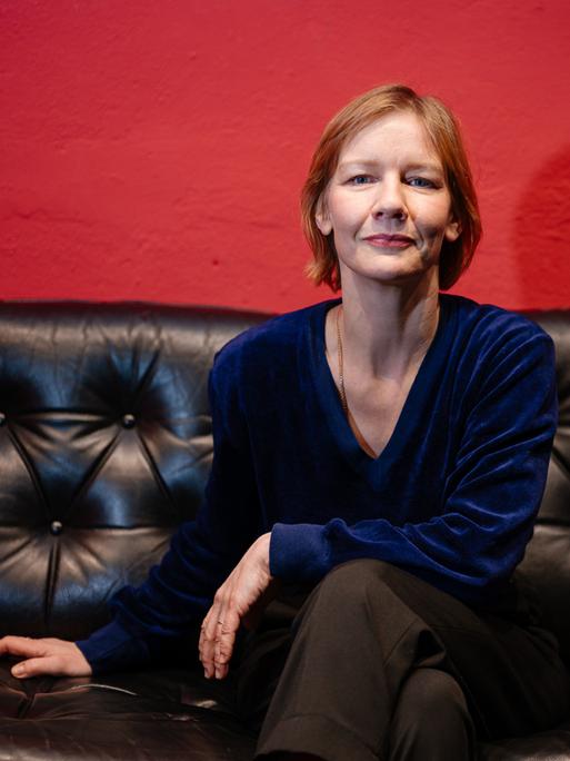 Die Schauspielerin Sandra Hüller sitzt auf einer schwarzen Couch in einem kleinen Saarbrücker Programmkino. 