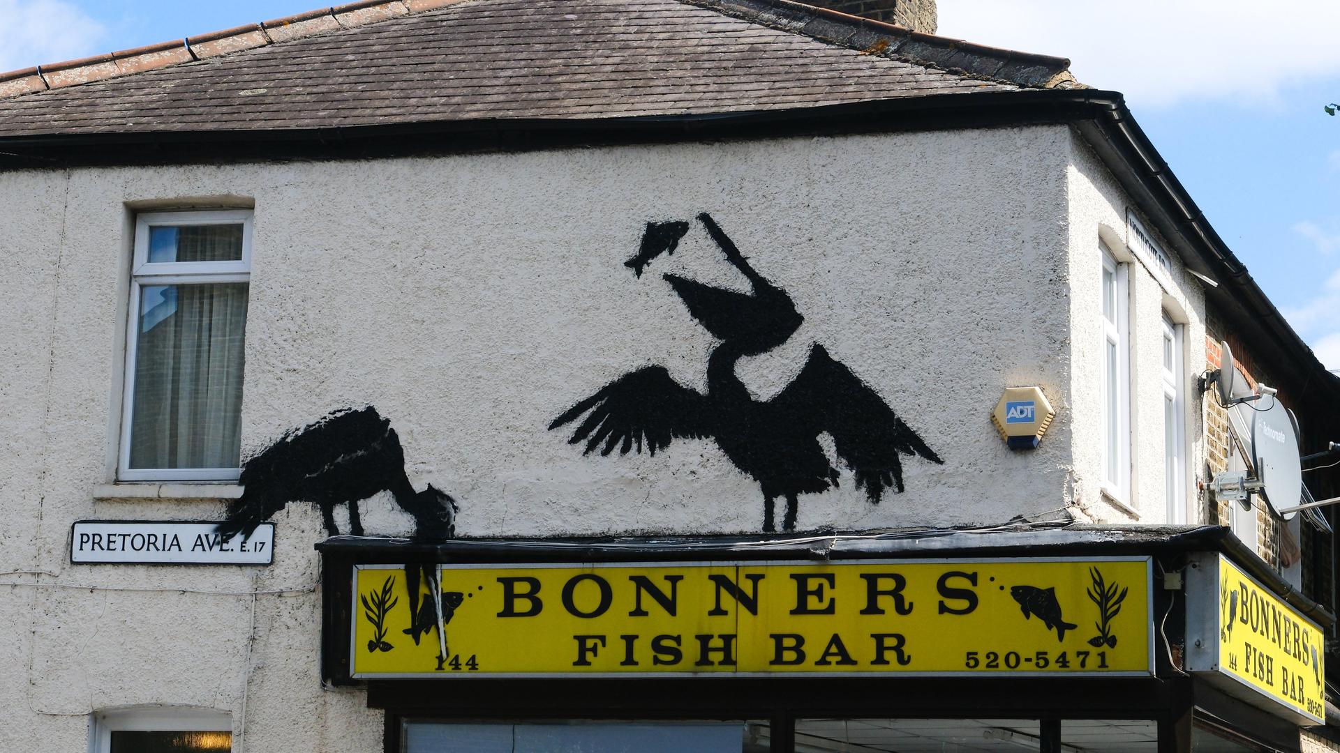 Ein gesprühter Pelikan isst einen Fisch auf einem Fish'n'Chips-Laden. Ein gesprühter Pelikan isst einen Fisch auf einem Fish'n'Chips-Laden.