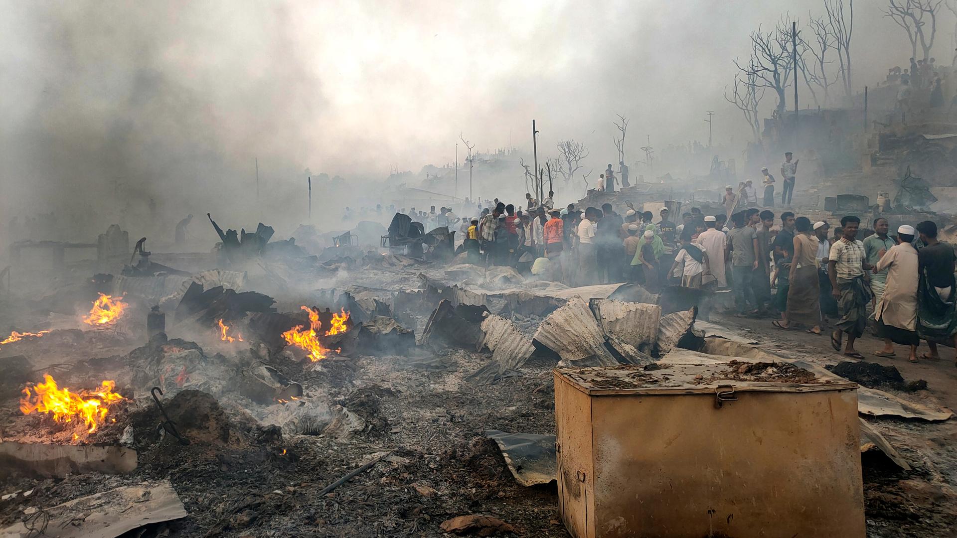 Flüchtlinge sind in einem Lager in dem Land Bangladesch zwischen ihren abgebrannten Hütten. 