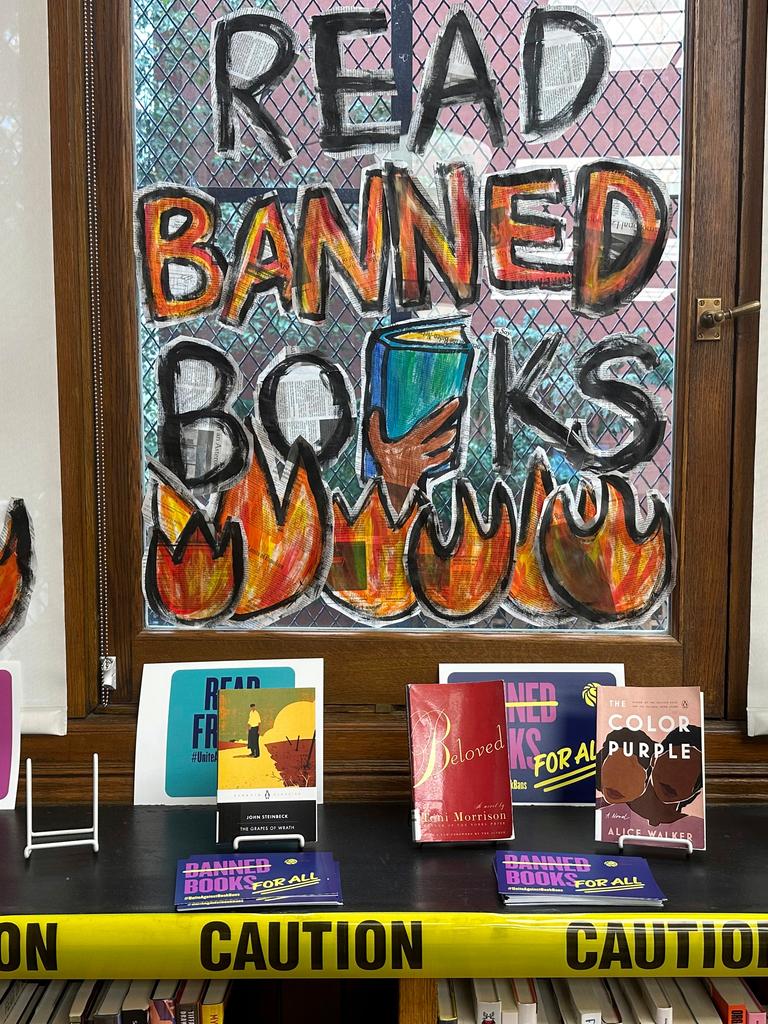 Hinter einem Büchertisch ist ein Fenster mit der denalten Aufschrift: Read banned books
