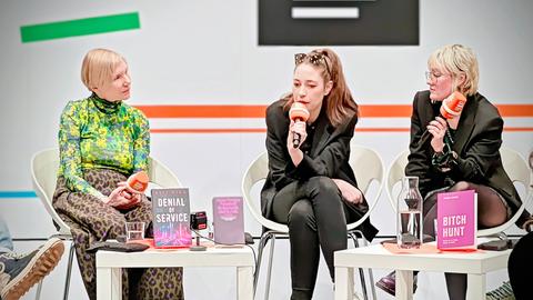Aiki Mira, Anna-Verena Nosthoff und Veronika Kracher (v.l.n.r.) sitzen mit Dlf-Mikrofonen hinter zwei kleinen Tischen am Deutschlandradio-Stand auf der Leipziger Buchmesse und sprechen miteinander