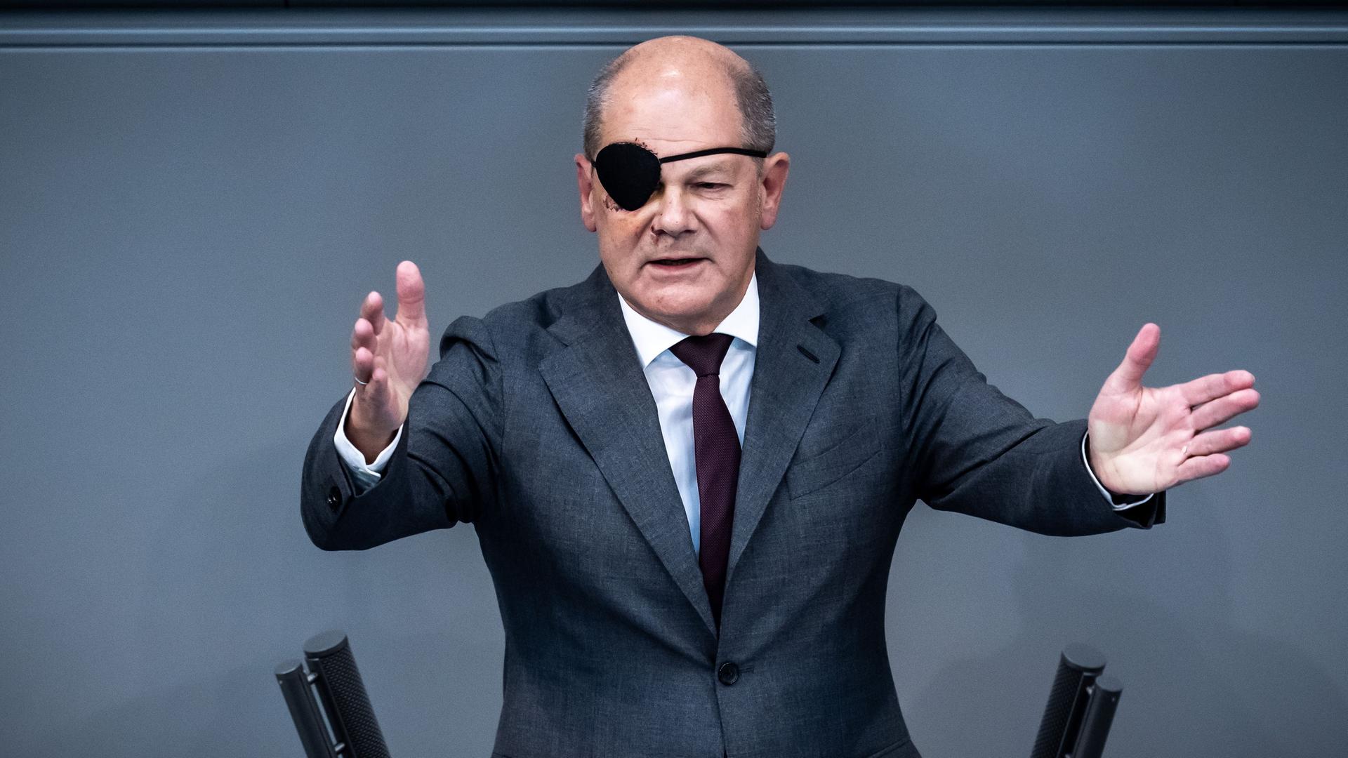 Bundes-Kanzler Olaf Scholz redet im Bundestag.Er trägt eine Augen-Klappe, weil er sich bei einem Sturz im Gesicht verletzt hat.