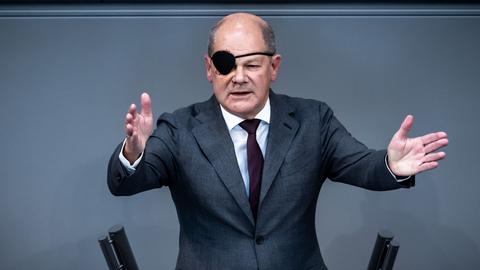 Berlin: Bundeskanzler Olaf Scholz spricht mit geöffneten Armen bei der Generaldebatte des Bundestags.