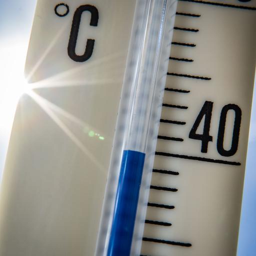 Ein Außenthermometer zeigt vor dem blauen Himmel und der Sonne eine Temperatur von nahezu 40 Grad Celsius an. 