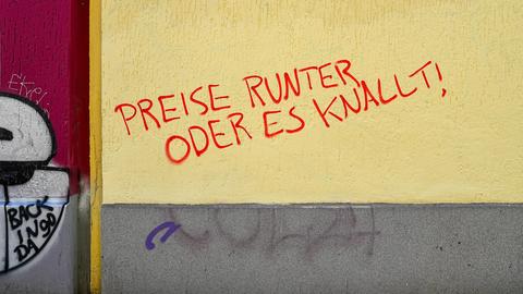 Berlin-Neukölln, auf einer verputzten, gelben Wand eines Hauses steht in roter Farbe: "PREISE RUNTER ODER ES KNALLT!"