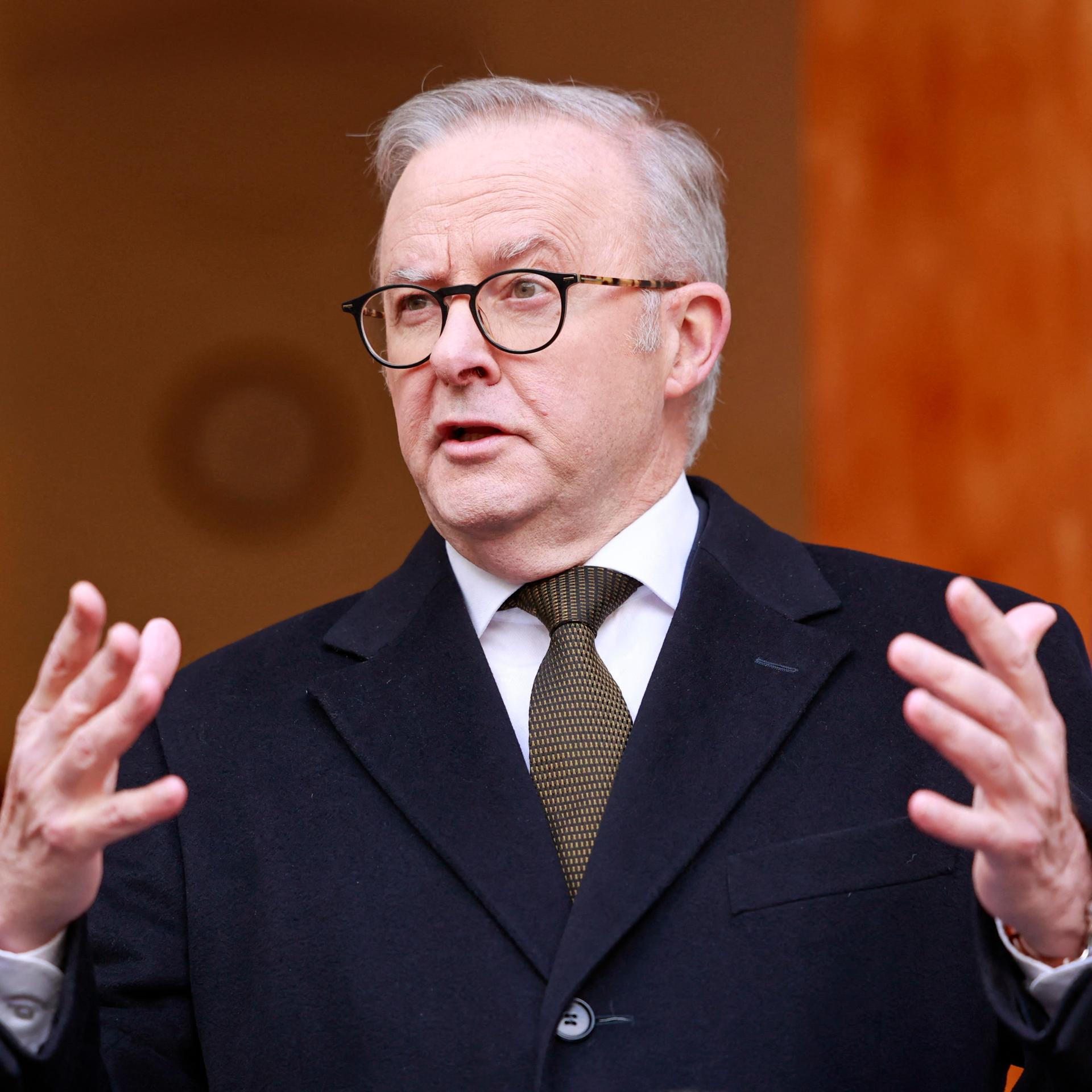 Australiens Premierminister Albanese spricht und hebt dabei beide Arme an. 