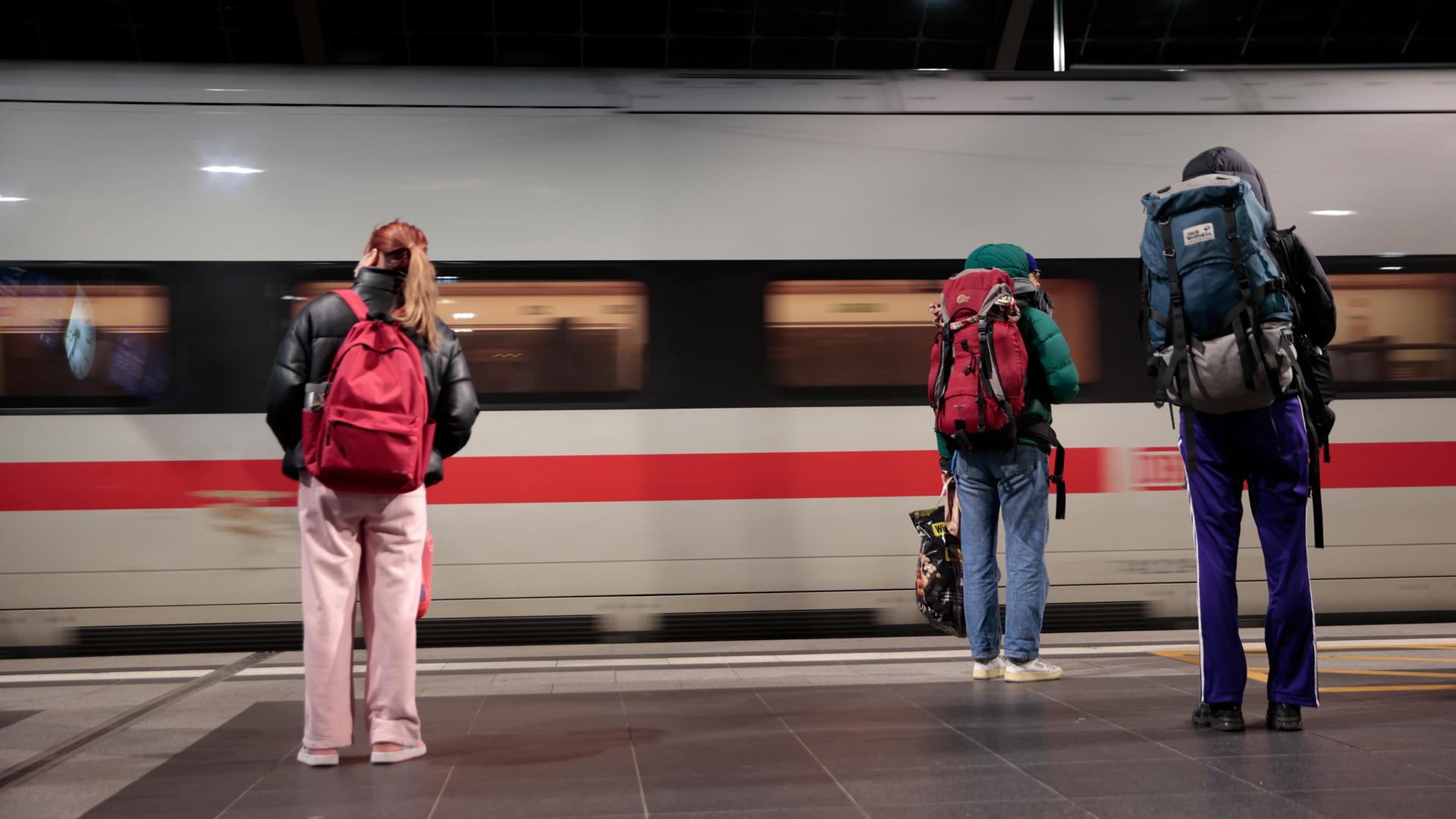 Reisende warten im Berliner Hauptbahnhof während der Einfahrt eines Zuges ICE am Bahnsteig.