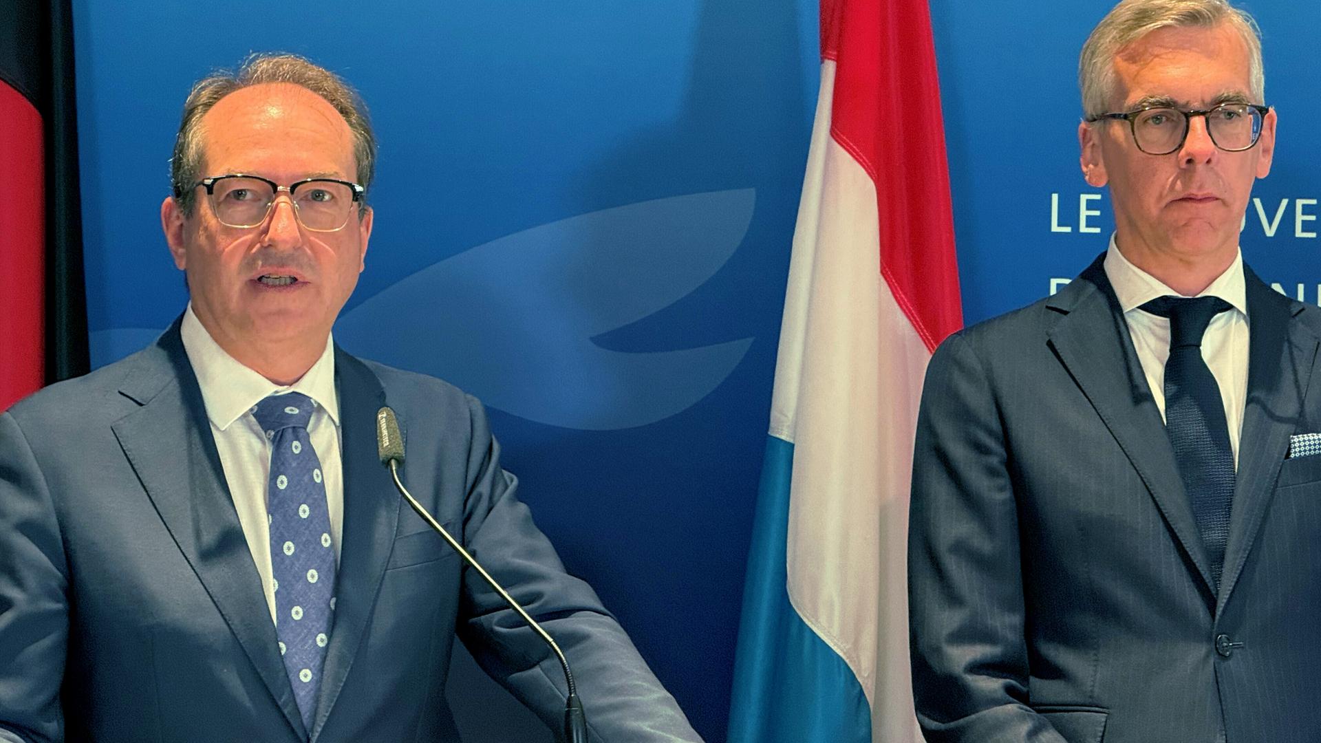 Bundesinnenminister Alexander Dobrindt (CSU) und Luxemburgs Innenminister Léon Gloden während einer Pressekonferenz, zwischen ihnen steht die luxemburgische Landesflagge