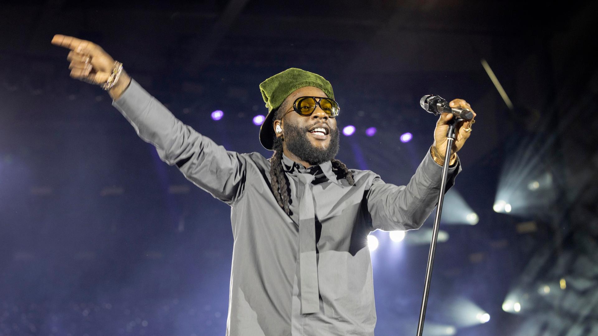 Burna Boy in komplett grauem Dress mit grüner Kopfbedeckung bei einem Auftritt in der Berliner Waldbühne Burna Boy in komplett grauem Dress mit grüner Kopfbedeckung bei einem Auftritt in der Berliner Waldbühne