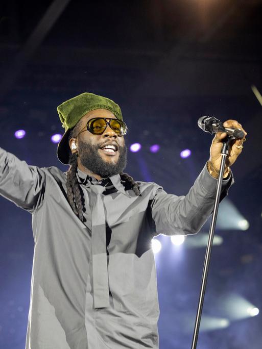 Burna Boy in komplett grauem Dress mit grüner Kopfbedeckung bei einem Auftritt in der Berliner Waldbühne