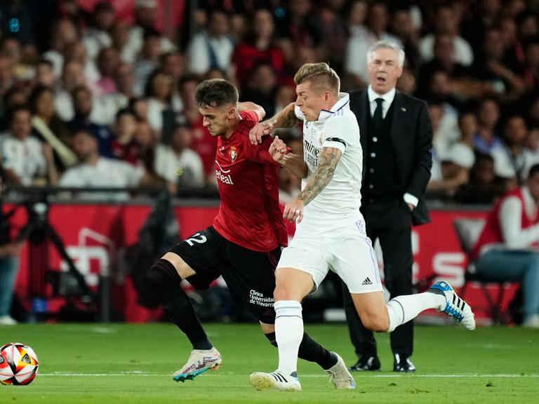 Zwei Fußballspieler kämpfen um den Ball. Es sind Toni Kroos von Real Madrid im weißen Trikot  und Aimar Oroz von CA Osasuna, rotes Trikot.