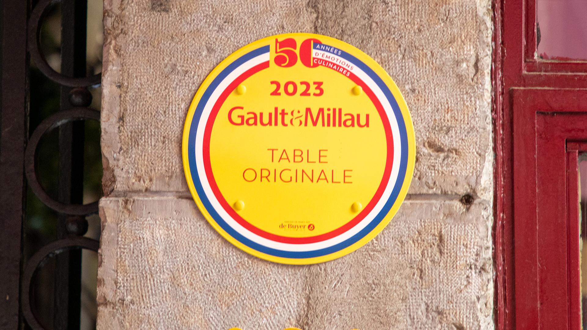 Ein gelbes Schild mit der Aufschrift Gault & Millau aus Frankreich. Ein gelbes Schild mit der Aufschrift Gault & Millau aus Frankreich.