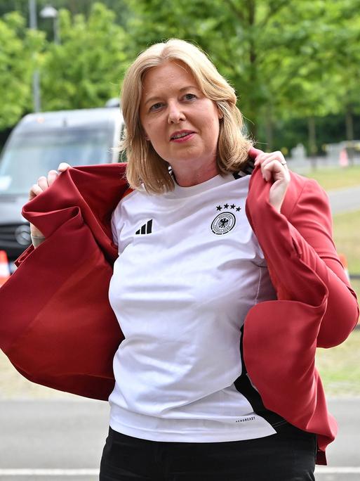 Bundestagspräsidentin Bärbel Bas zieht einen roten Blazer über ein Deutschlandtrikot.