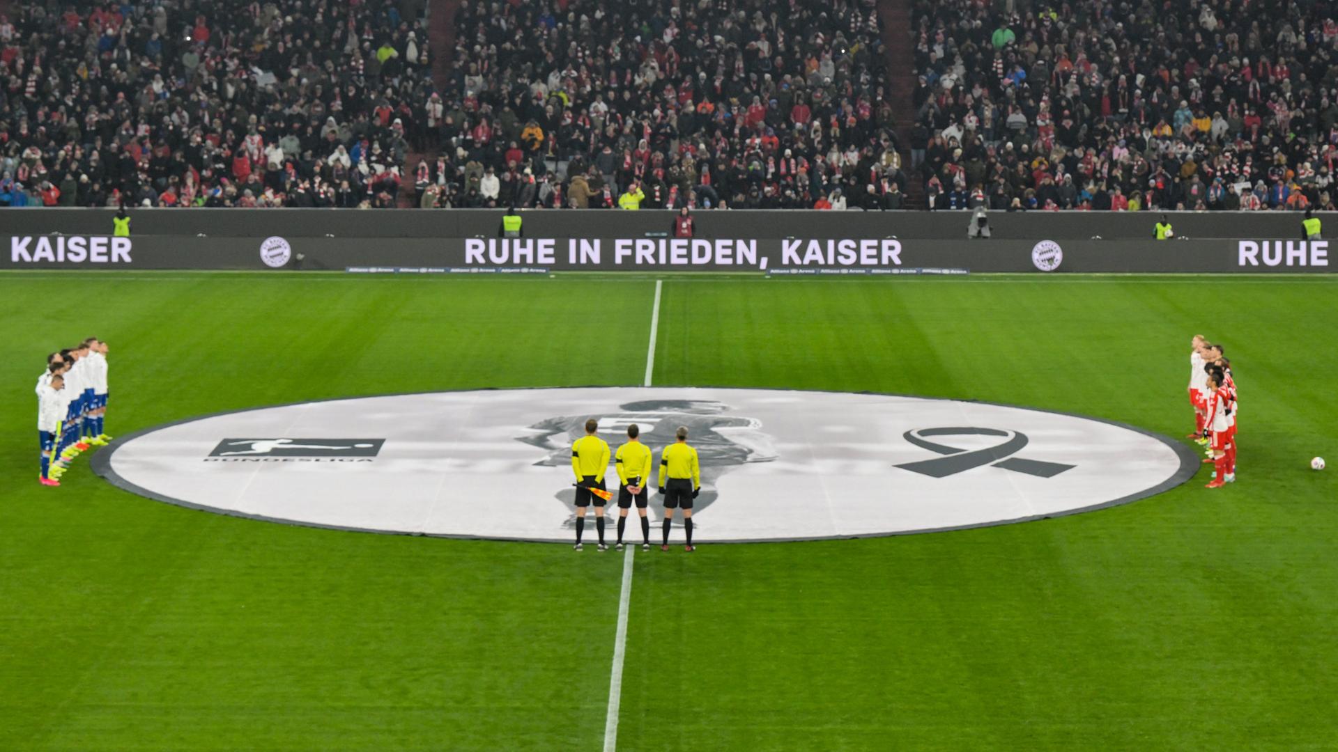 Im Stadion des FC Bayern München halten am 17. Spieltag stehen die Mannschaften von Bayern und Hoffenheim mit den Schiedsrichtern rund um den Mittelkreis während einer Gedenkminute für den verstorbenen Franz Beckenbauer. Aufnahme vom 12.01.22024. Im Stadion des FC Bayern München halten am 17. Spieltag stehen die Mannschaften von Bayern und Hoffenheim mit den Schiedsrichtern rund um den Mittelkreis während einer Gedenkminute für den verstorbenen Franz Beckenbauer. Aufnahme vom 12.01.22024.