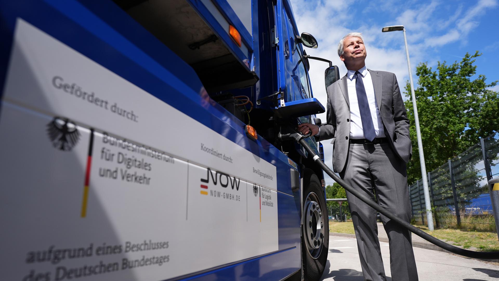 Verkehrsminister Bilger (CDU) steht neben einem E-Lkw und informiert sich über das vom Ministerium geförderte Projekt öffentlich zugänglicher Ladeinfrastruktur für Elektroautos und E-Lkw.
