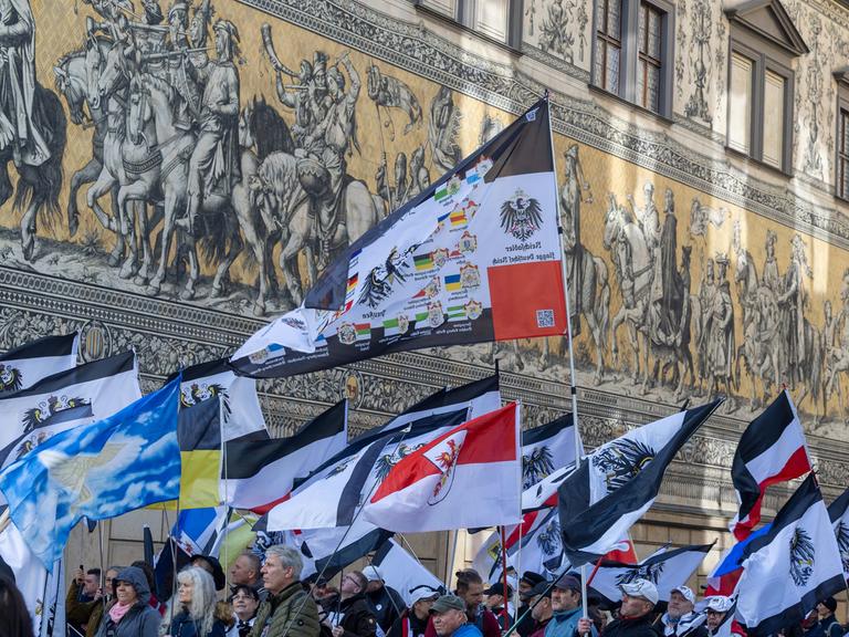 Teilnehmer einer Demonstration ziehen mit Flaggen vom Königreich Preußen (schwarz-weiß-schwarz mit Adler) über die Dresdener Augustusstraße am Fürstenzug vorbei.