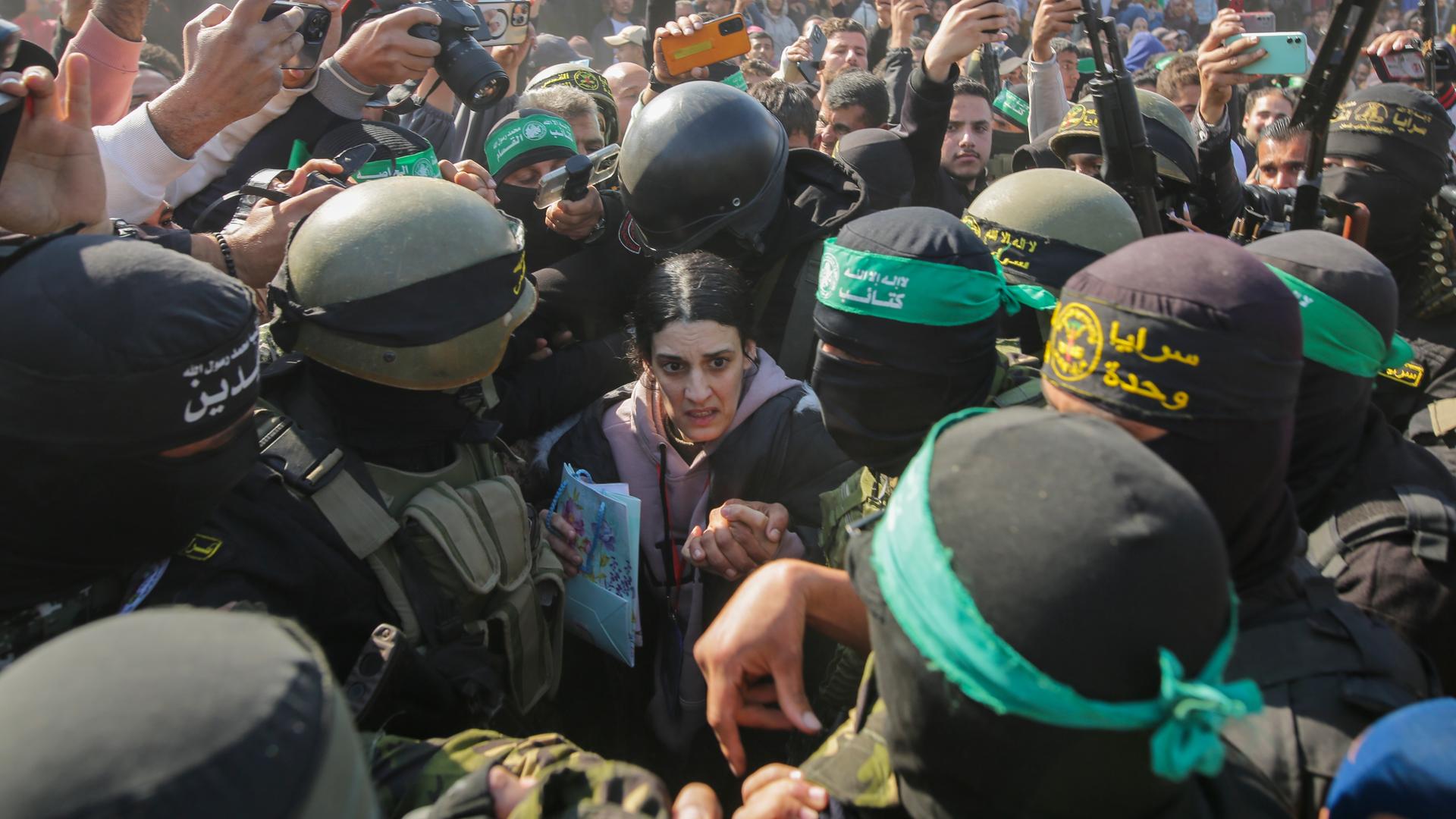 Eine Frau wird von Kämpfern der Hamas und des Islamischen Dschihad eskortiert, als sie dem Roten Kreuz übergeben wird.