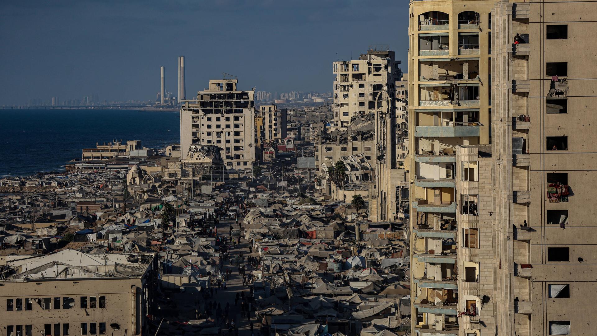 Ein Blick über einige Hochhäuser in Gaza-Stadt, dazwischen sind Zeltunterkünfte zu sehen. Viele der Gebäude sind zerstört. 