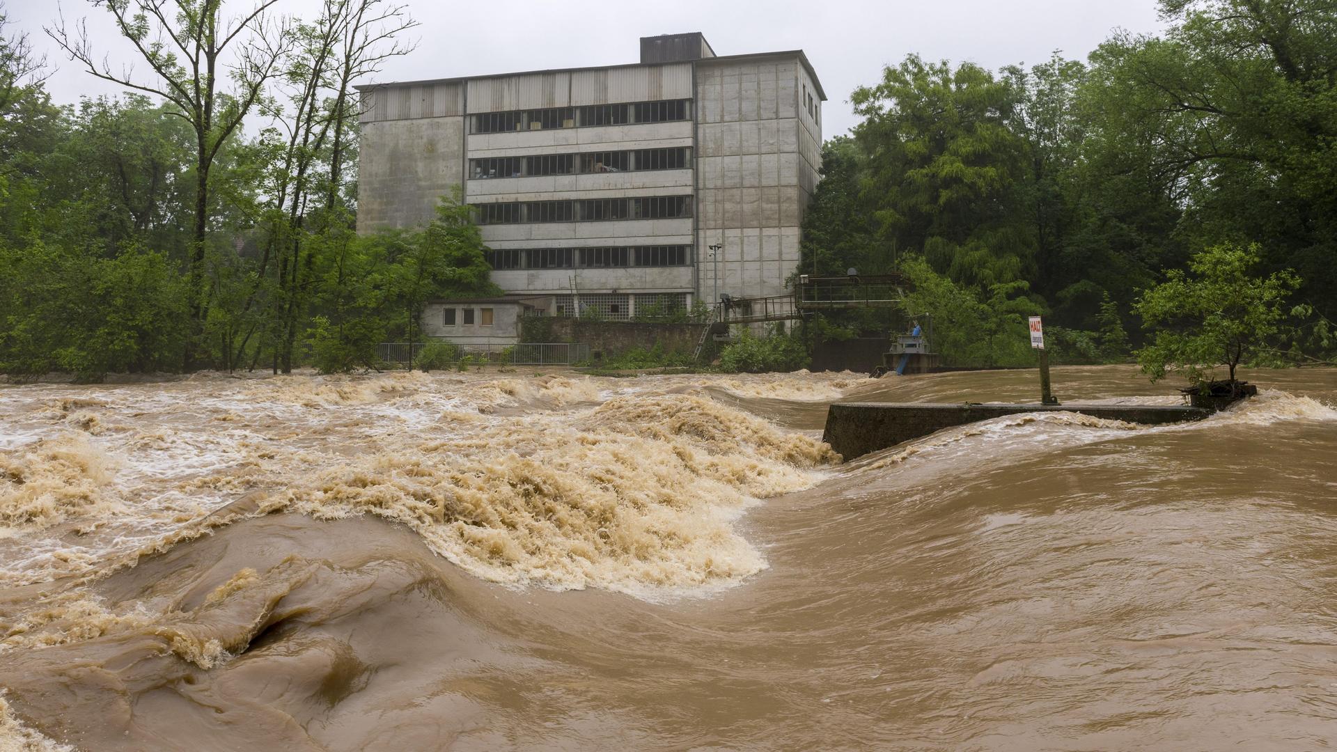 Ein Haus steht sehr nah an einem Fluss, der über die Ufer getreten ist und sehr schnell fließt. Ein Haus steht sehr nah an einem Fluss, der über die Ufer getreten ist und sehr schnell fließt.