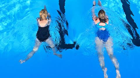 Zwei Badegäst beim Schwimmen in einem Freibad.