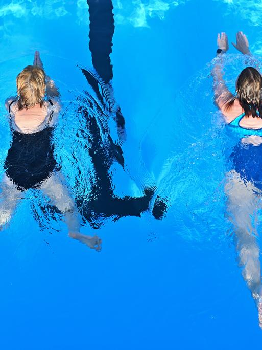 Zwei Badegäst beim Schwimmen in einem Freibad.