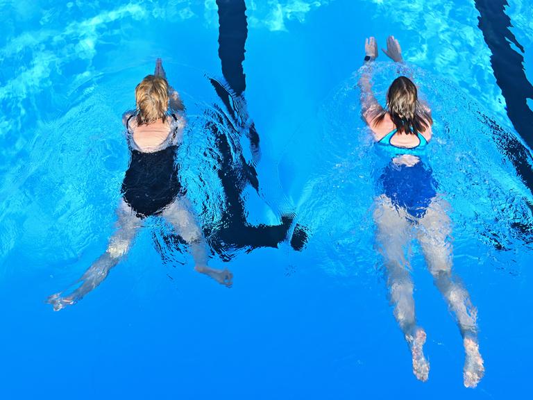 Zwei Badegäst beim Schwimmen in einem Freibad.