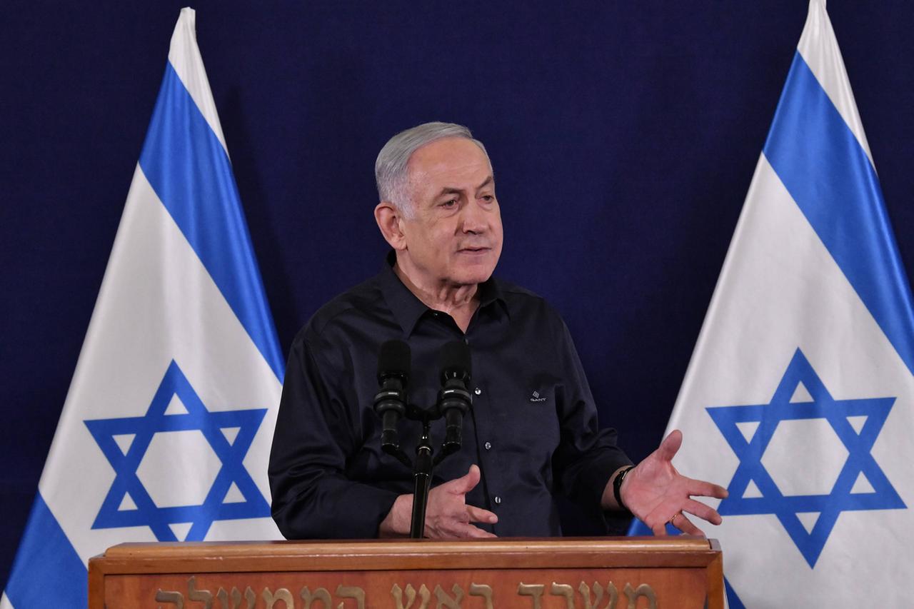 Israels Ministerpräsident Netanjahu steht an einem Rednerpult vor zwei israelischen Flaggen.
