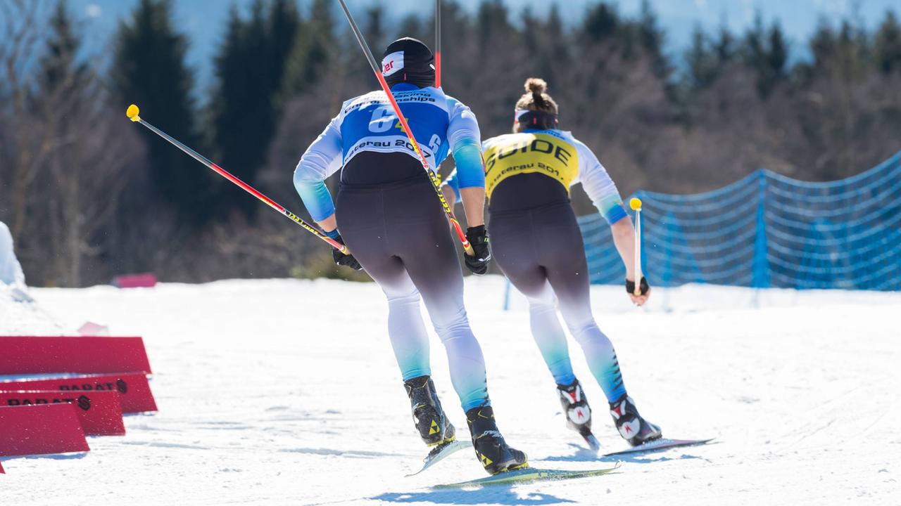 Zwei Skiläuferinnen hintereinander, die vordere führt die hinter über die Strecke.