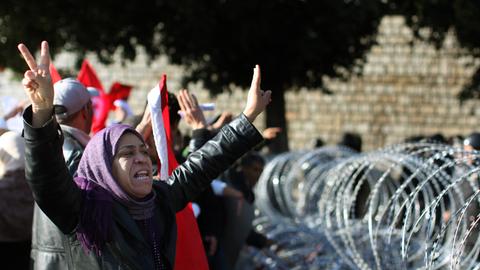 Januar 2011 in Tunis / Tunesien: Eine Demonstrantin mit Kopftuch fordert lautstark Soldaten auf, sie durch die Stacheldrahtbarrikade vor dem Büro des tunesischen Premierministers zu lassen. 